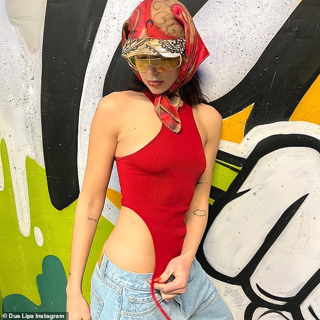 Dua Lipa showcasing her outfit featuring hip cutouts